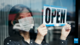 mask wearing person flips sign to open