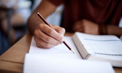 Closeup shot of a young man writing on a note pad