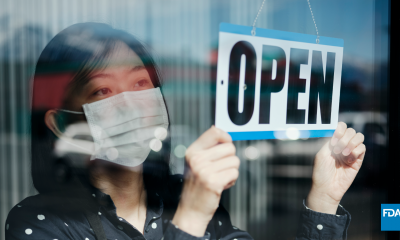 mask wearing person flips sign to open